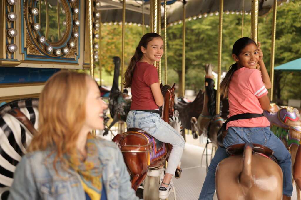 Young girls ride a carousel.
