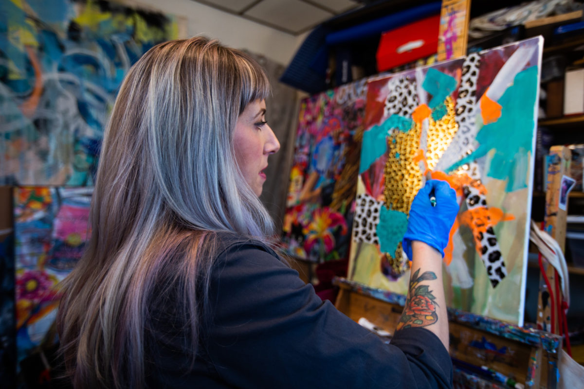 a woman works on a piece of art at Night Owl Gallery