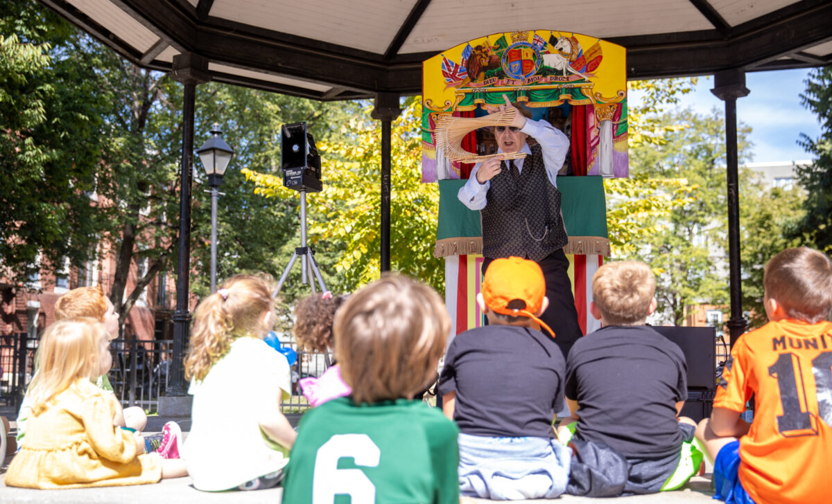 A performer holds up an object to a crowd of children