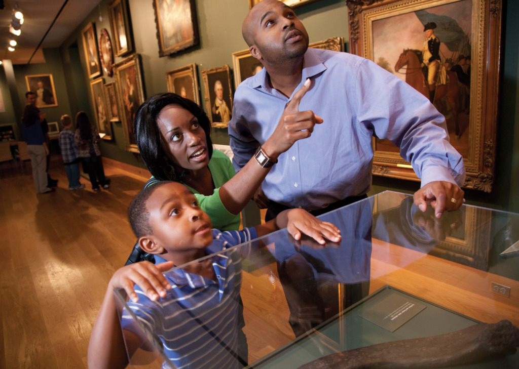 Ken Stanek Photography A man, woman and child look at a piece of art in a museum, not visible to the viewer of the photo. The woman points up with a curious expression.
