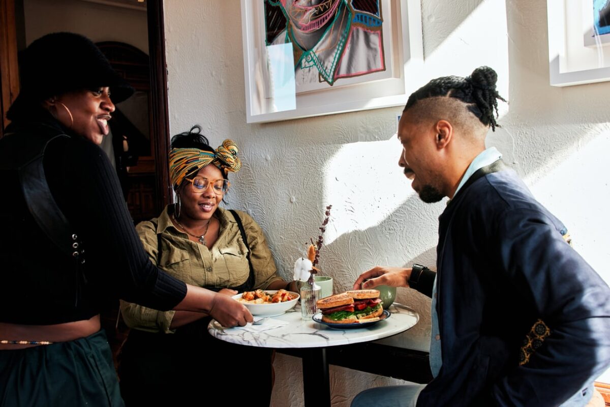 A server places shrimp and grits in front of a Black couple seated at a table