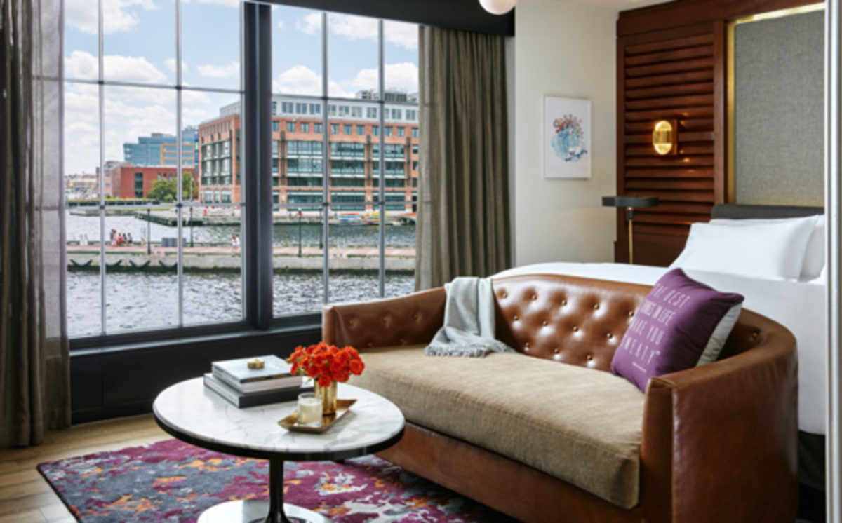 Hotel room with a bed and a couch with a view of the harbor from the window.
