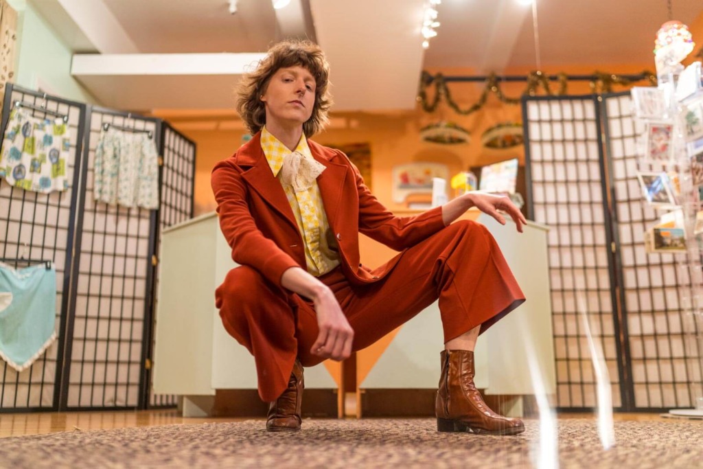 A person posing with their legs propSarah Autrey posing in a yellow and burnt orange vintage suit at Get Shredded Vintage in Baltimore.