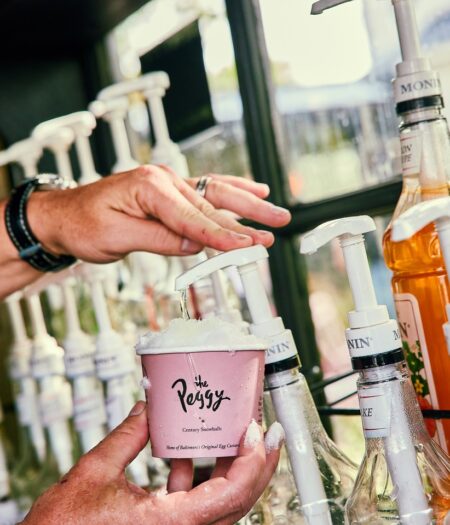 hand pushing syrup into a cup with ice to make a snowball