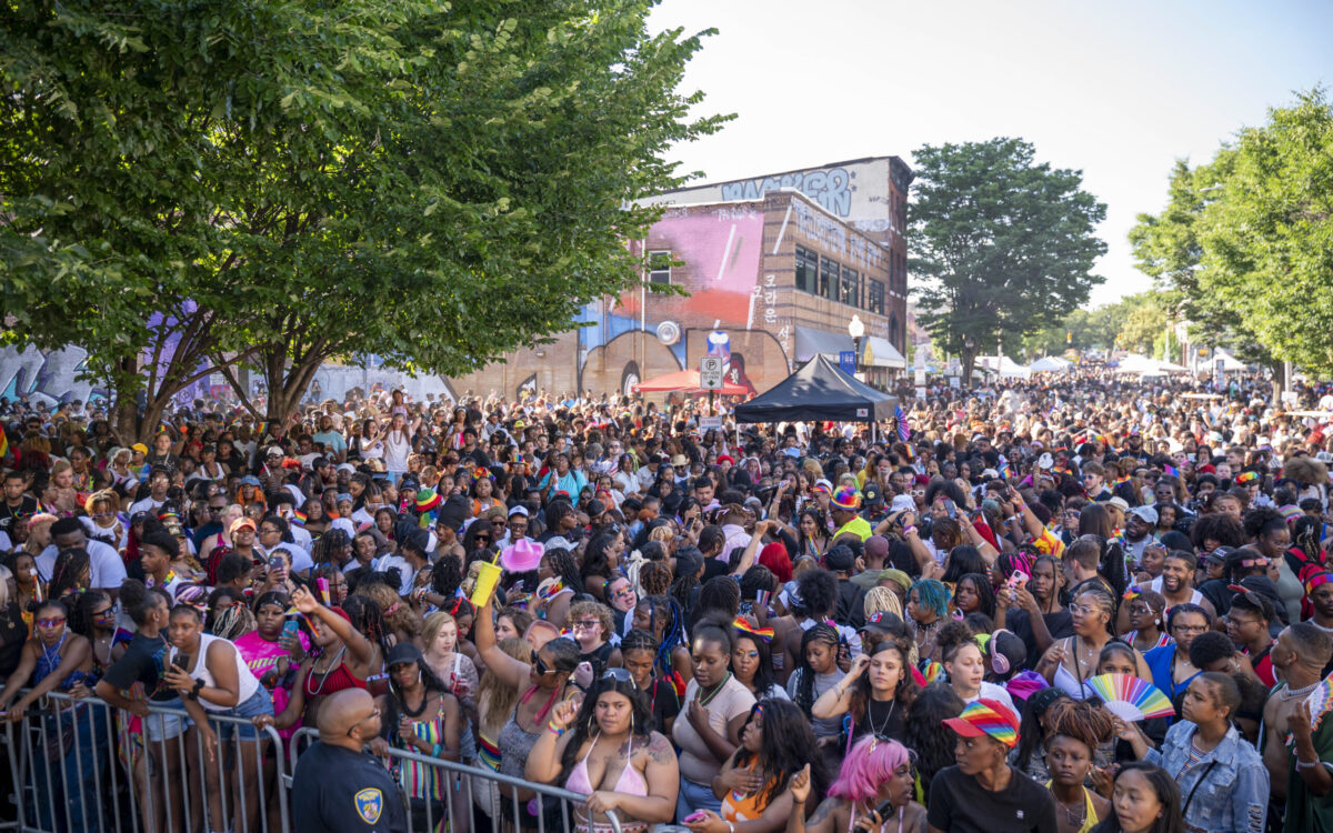 A crowd of people gather behind a fence
