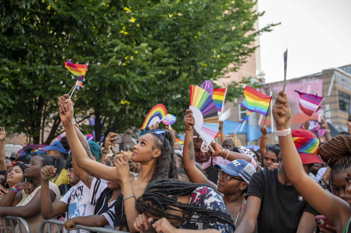 A closer shot of people in a crowd waving rainbow flags
