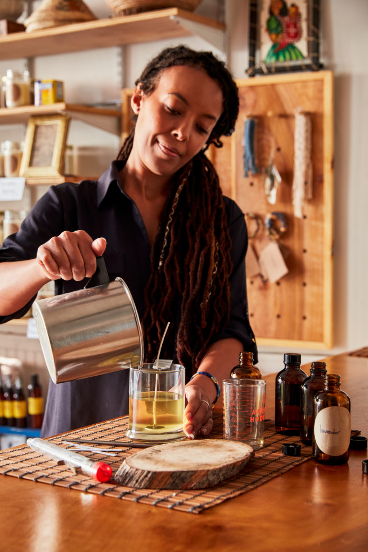 a woman pours wax into a glass container